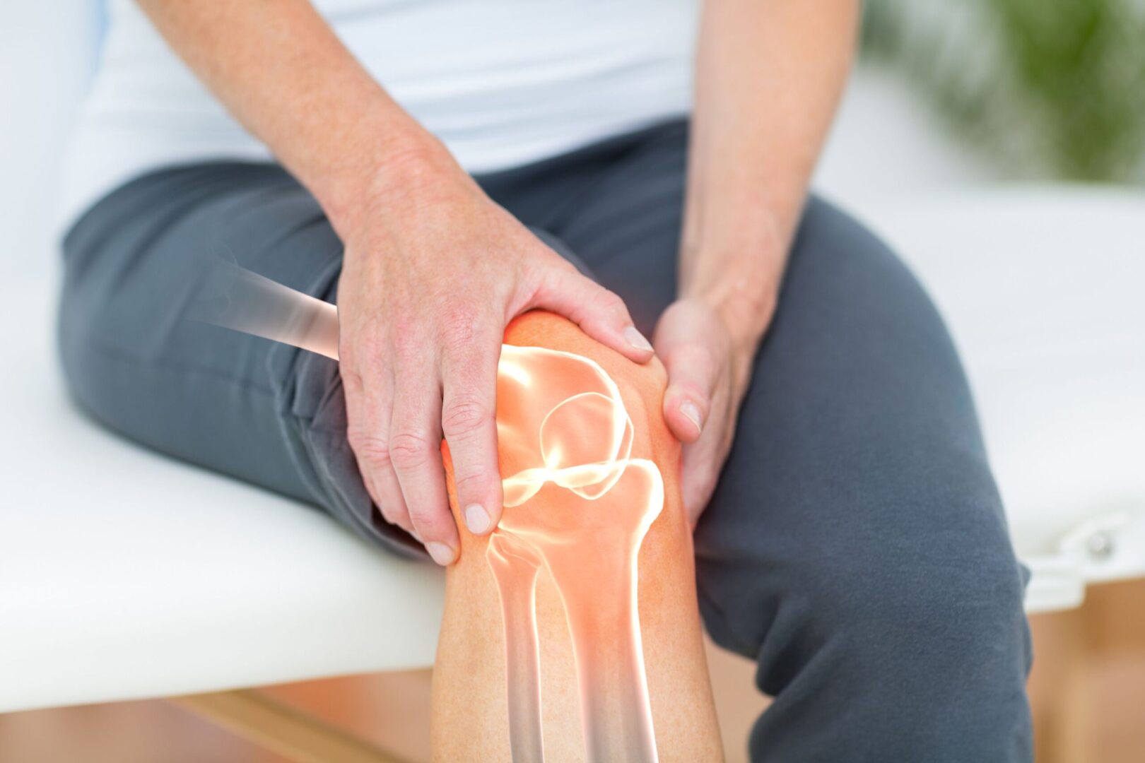 A person holding their knee with the image of an injury.