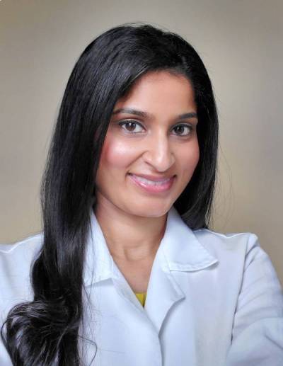 A woman in white lab coat smiling for the camera.